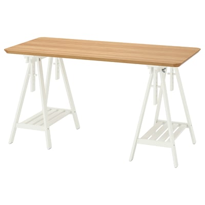 An ANFALLARE desk with a light wooden top and white trestle legs. The design is simple and functional, featuring an adjustable trestle.
