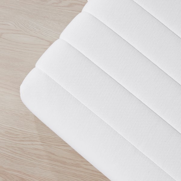 Close-up of firm, white mattress on wooden floor. Shows detailed texture and craftsmanship.