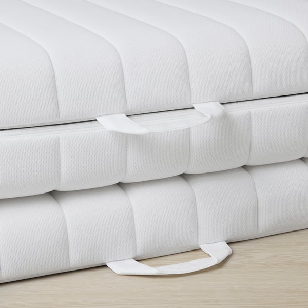 A close-up of a white mattress, showcasing its firm, evenly constructed layers of natural coir and foam, indicating high-quality craftsmanship.