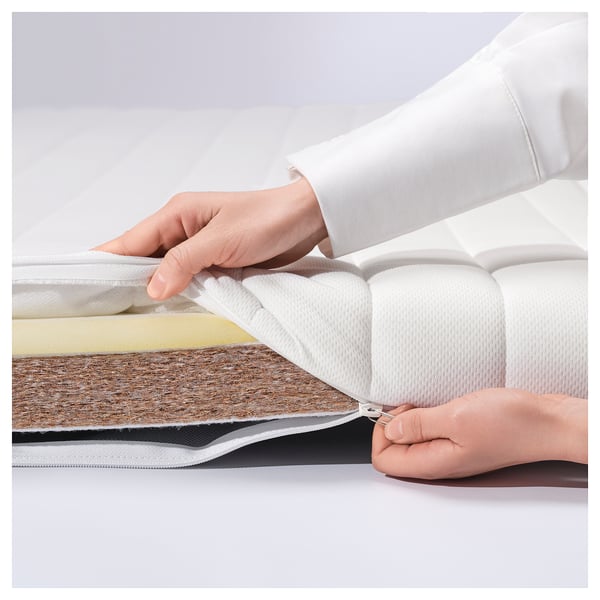 A person unzips a white ÅNNFJÄLLET mattress, revealing its layered design.