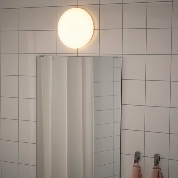A modern ceiling lamp in a tiled bathroom, emitting a soft, even light. Its wired for indirect lighting and suitable for bathroom use.
