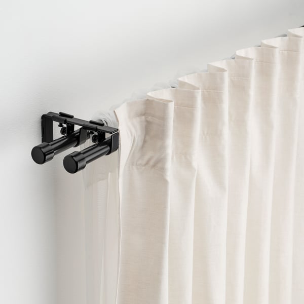Black curtain rod set with white curtains, holding them neatly against a light wall.