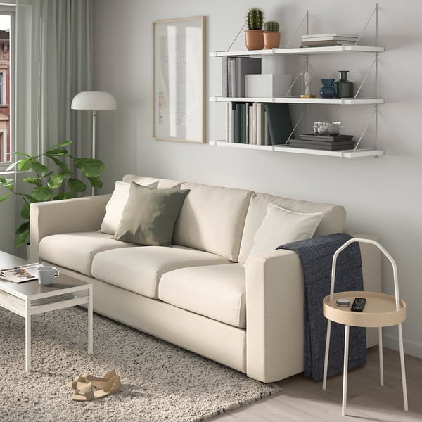Modern living room with BERGSHULT shelf, beige sofa, plant, and lamps.