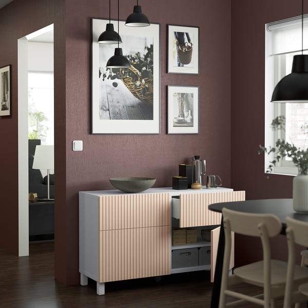 Sideboard with shelves and drawers, adjustable hinges. It is wall-mounted with a large bowl on top. Above it, hanging photos on a purple wall.