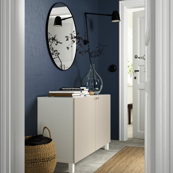 Modern hallway with BESTÅ sideboard, books, vase, and mirror.