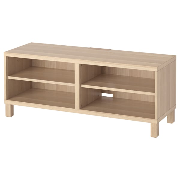 The ikea BESTÅ tv bench in white oak. It has an open design with two shelves for storage.