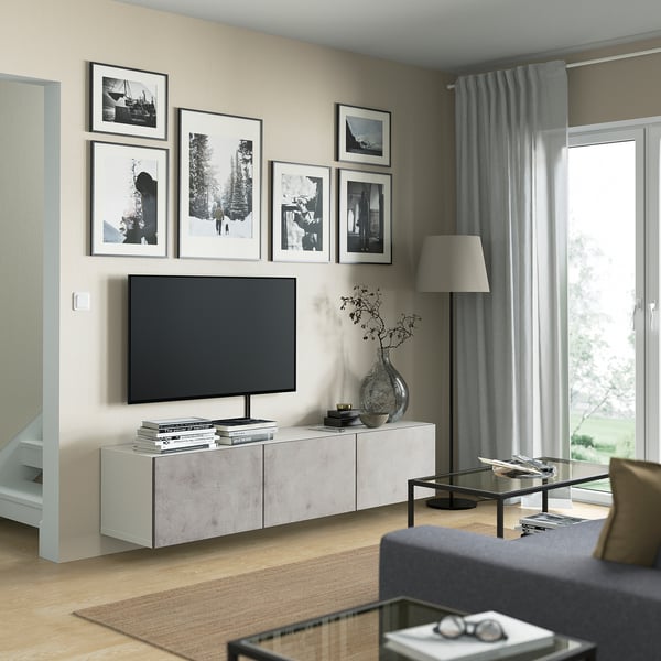 Modern living room with BESTÅ tv stand, flat screen tv, grey curtains, light wood floor, bookshelf, vase, and glass coffee table.