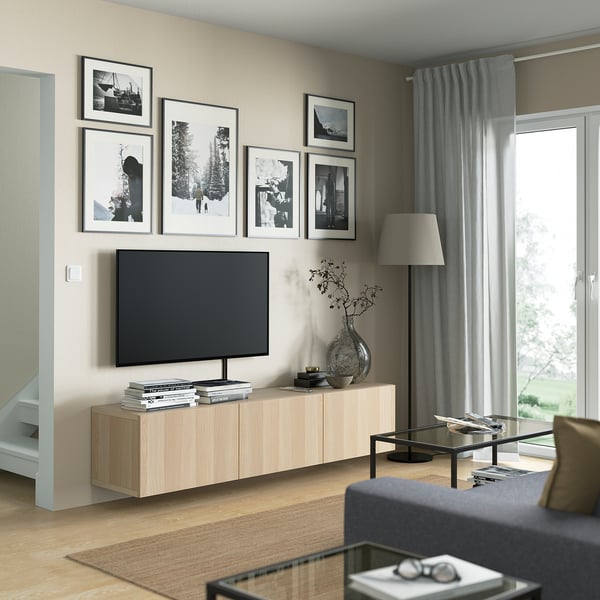 Modern living room with BESTÅ tv bench, flat screen tv, and decorative items. Large windows with curtains create a cosy, organised space.