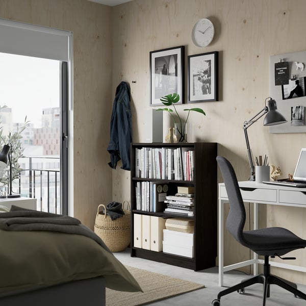 Minimalist office with BILLY bookcase, desk, office chair, laptop, plant, and city view window.