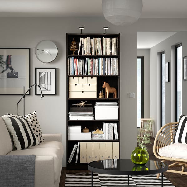 Modern living room with BILLY bookcase, rug, and sofa pillow.