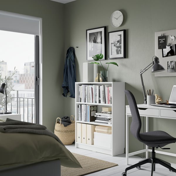 Modern bedroom featuring BILLY white bookshelf with green walls, black accents, and natural light from a large window.