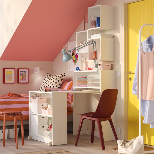 White BILLY bookcase with foldable table, blue lamp, brown chair, red/white decor, abstract art, yellow door with clothes.