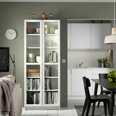 Modern living room with BILLY bookcase, kitchenette, and soft lighting.