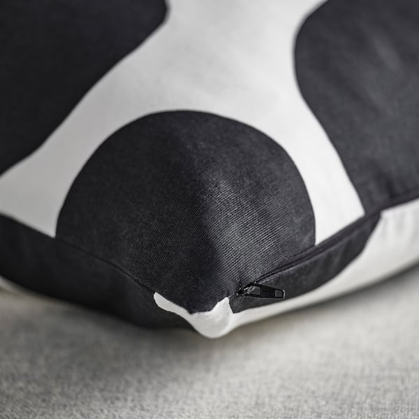 Close-up of a soft, black, and white dot-patterned cushion cover with a hidden zip, showing its quality texture and design.