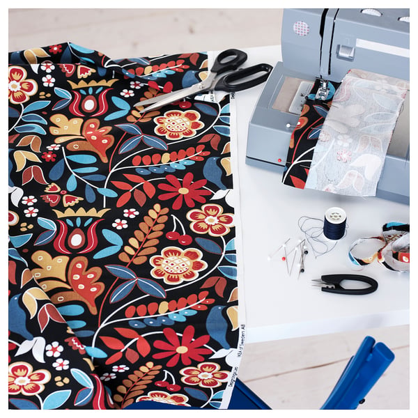 Colourful floral fabric, scissors, and sewing machine on table, showcasing craft and design tools for creating home decor.