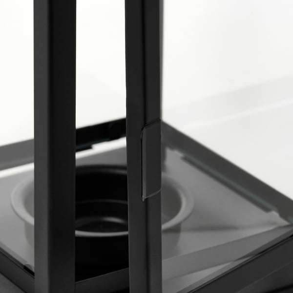 Black lantern with clear glass front, sturdy metal frame, and handle, photographed indoors.