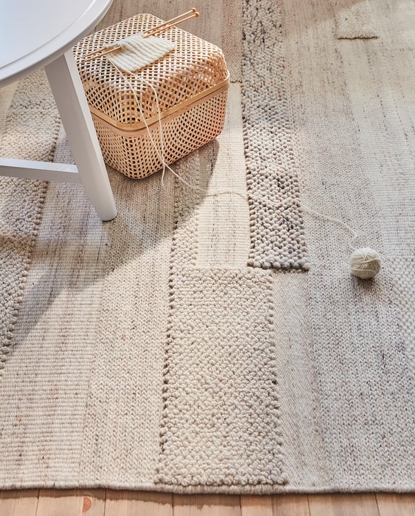 BRÖNDEN neutral woven rug on wooden floor with basket.