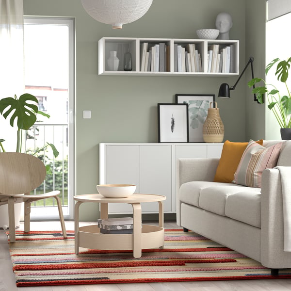 Modern living room with multicolor handwoven rug under grey sofa & plants.