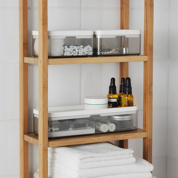 Wooden bathroom shelf with transparent storage bins and neatly folded towels.