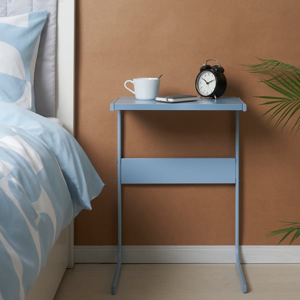 Small blue bedside table with alarm clock, cup, and phone. Ideal for keeping essentials close.