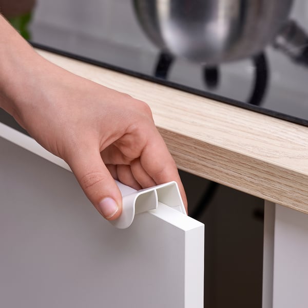 Person instals DRAGSMARK handle on cabinet without drilling.