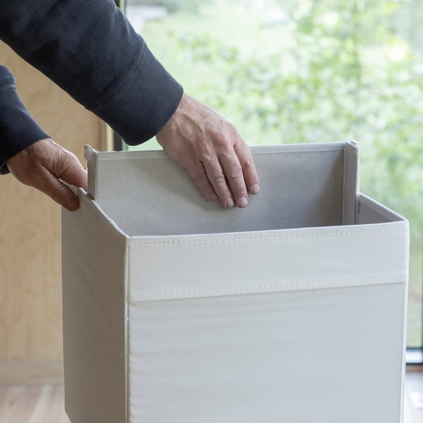 Hands placing a removable divider inside a storage box, dividing it into sections.