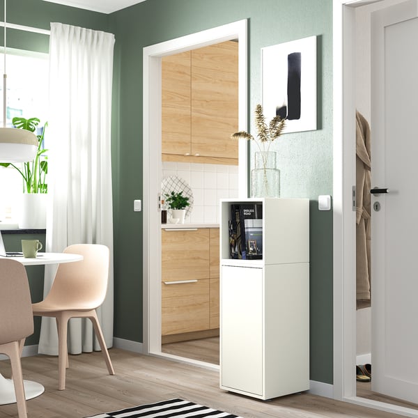 Modern green room EKET white storage unit near kitchen. Tall unit with glass top, plant, and decor.
