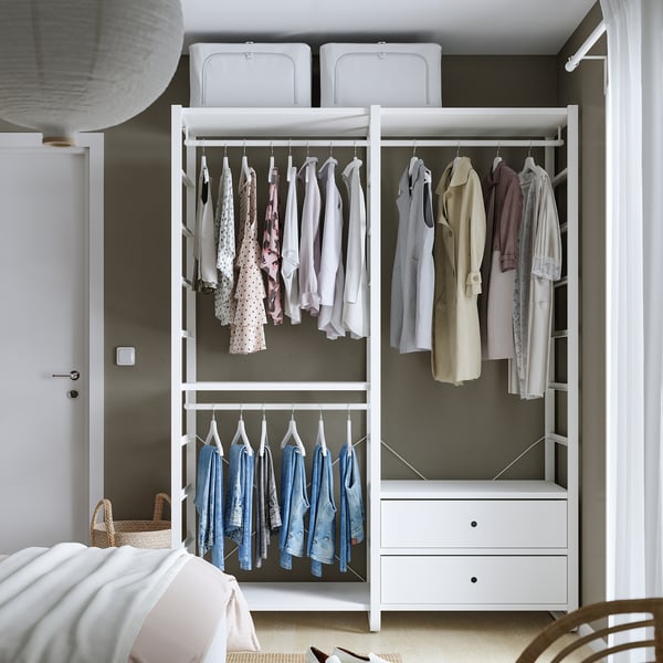 Modern open closet displaying clothes on hangers, featuring adjustable shelves and drawers for versatile storage.