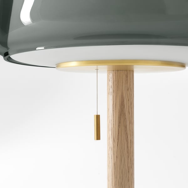 A modern lamp with a sleek brass and wood design. It a clear glass shade and a sturdy marble base.