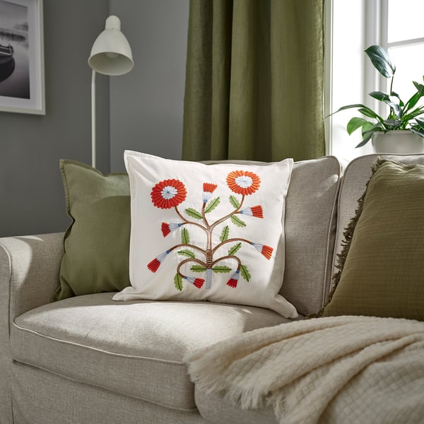 Beige sofa with red/green floral FACELIOR cushion, green blanket & curtains, plant. 100% cotton.