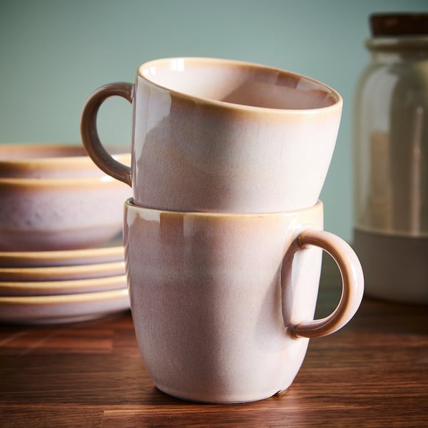 Two glazed mugs stacked on a wooden table, showcasing a rustic surface and practical design for serving coffee or tea.