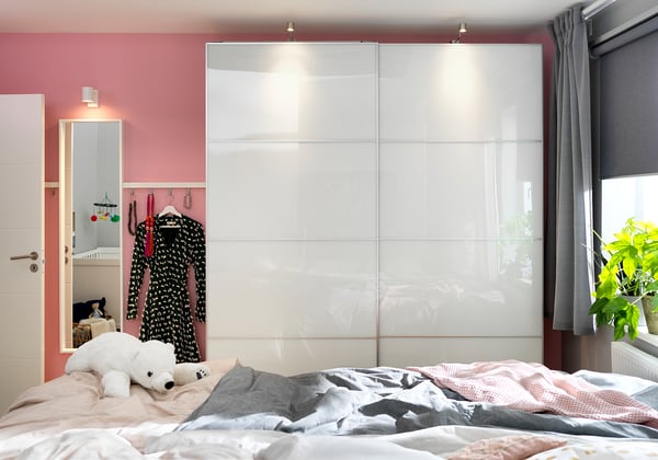Modern bedroom with FÄRVIK wardrobe, glass panels, pink walls, grey bed linens, and a teddy bear.