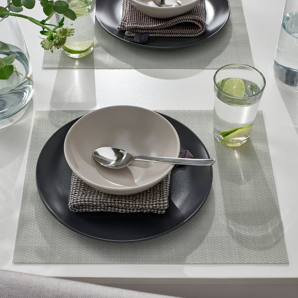 Table setting with FLYGFISK place mats, bowl, spoon, and drink with lime.