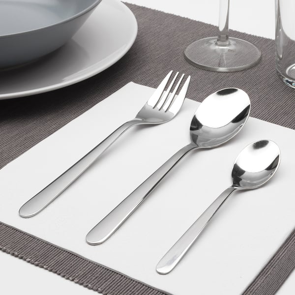Stainless steel cutlery set with fork, spoon, teaspoon on napkin. Elegant table setting.