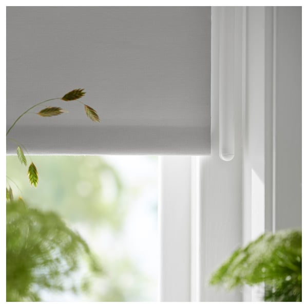 A FRIDANS white roller blind with a cordless design, partially covering a window. The screen fabric blocks light while allowing outdoor visibility.