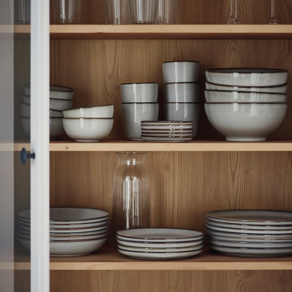 Grey stoneware on wooden shelves, plates & bowls, neat stack, sandy glaze.