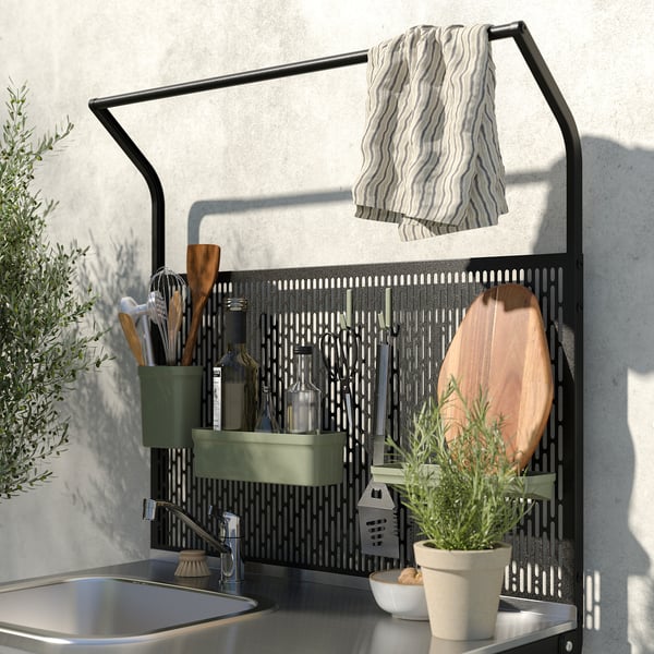 Modern kitchen setup with sink, accessories, and plants on a black metal rack.