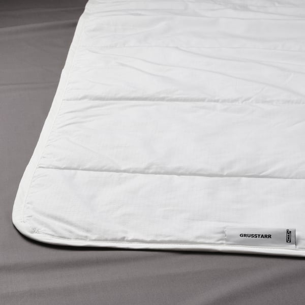 White duvet with a subtle dot pattern neatly placed on a grey bedsheet.