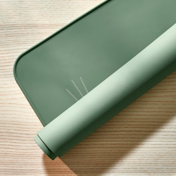 Green silicone place mat with cat design, protecting table from spills and scratches, easy to clean.