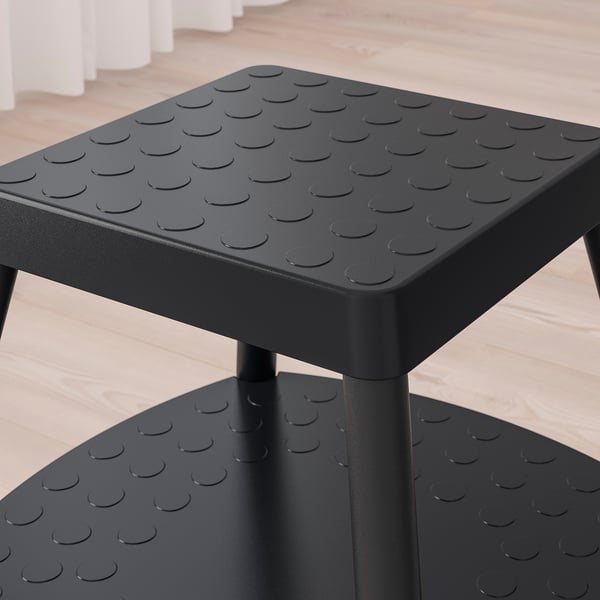 Black step stool with patterned textured surface, sturdy metal legs, two wide steps for stability.