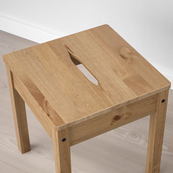 Simple wooden stool, light finish, natural wood grain visible, cut-out handle for easy movement.