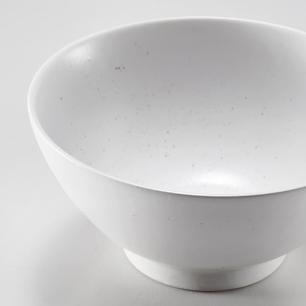 Sickness-free porcelain bowl, sleek white with subtle specks, wide rim, smooth texture, sits steadily