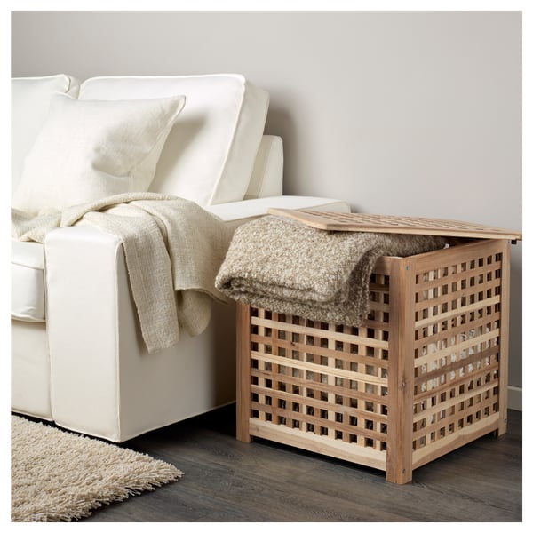 Wooden HOL side table with lattice, HOLding blankets beside sofa.