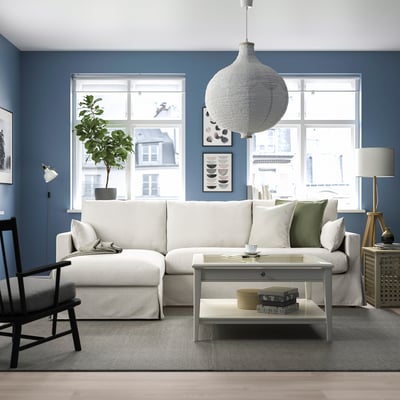 Modern living room with HYLTARP sectional sofa, green cushions, city view windows, and pendant lamp.