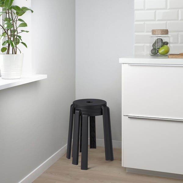 Black stackable stool beside white cabinets in kitchen.