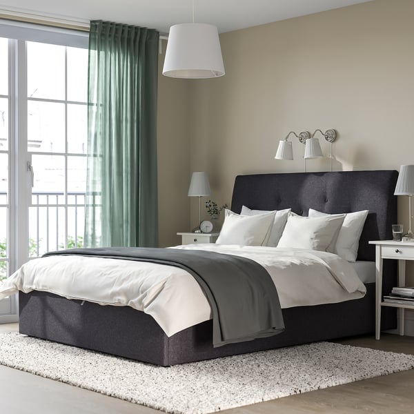 Cosy bedroom with dark grey IDANÄS bed, ottoman, & large window with green curtains.