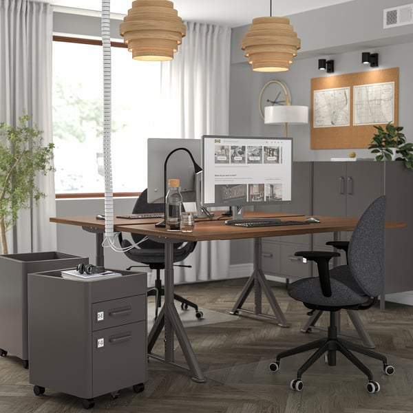 Modern office with IDÅSEN desks, adjustable chairs, and pendant lights. Computers and storage.