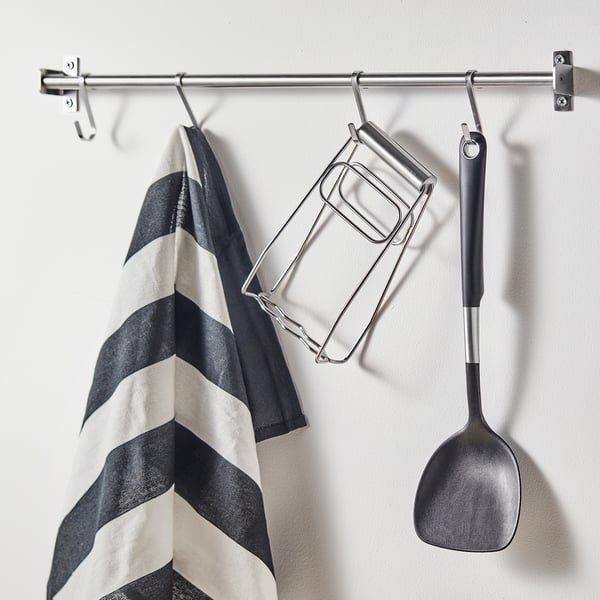 Kitchen tools hanging: striped towel, toaster rack, spatula on steel bar.