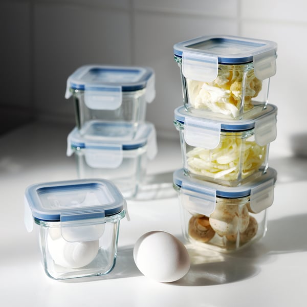Stacked glass containers with blue lids store food items, keeping contents visible and fresh.