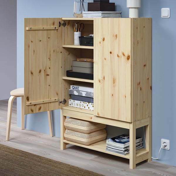 Wooden storage cabinet with open doors, shelves stocked with books and boxes, raised on underframe.